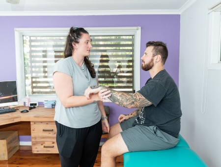 Female Physiotherapist examining male patient's arm for Help with DVA Claims in Sydney - Contact VHC today
