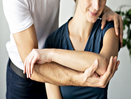 Male therapist hands holding female patient's arm and providing ongoing veterans health care Amberley - Contact VHC today